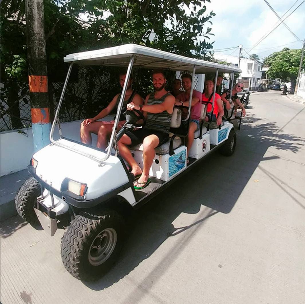 A group of guests in an eight-seat golf cart on a San Andrés street.