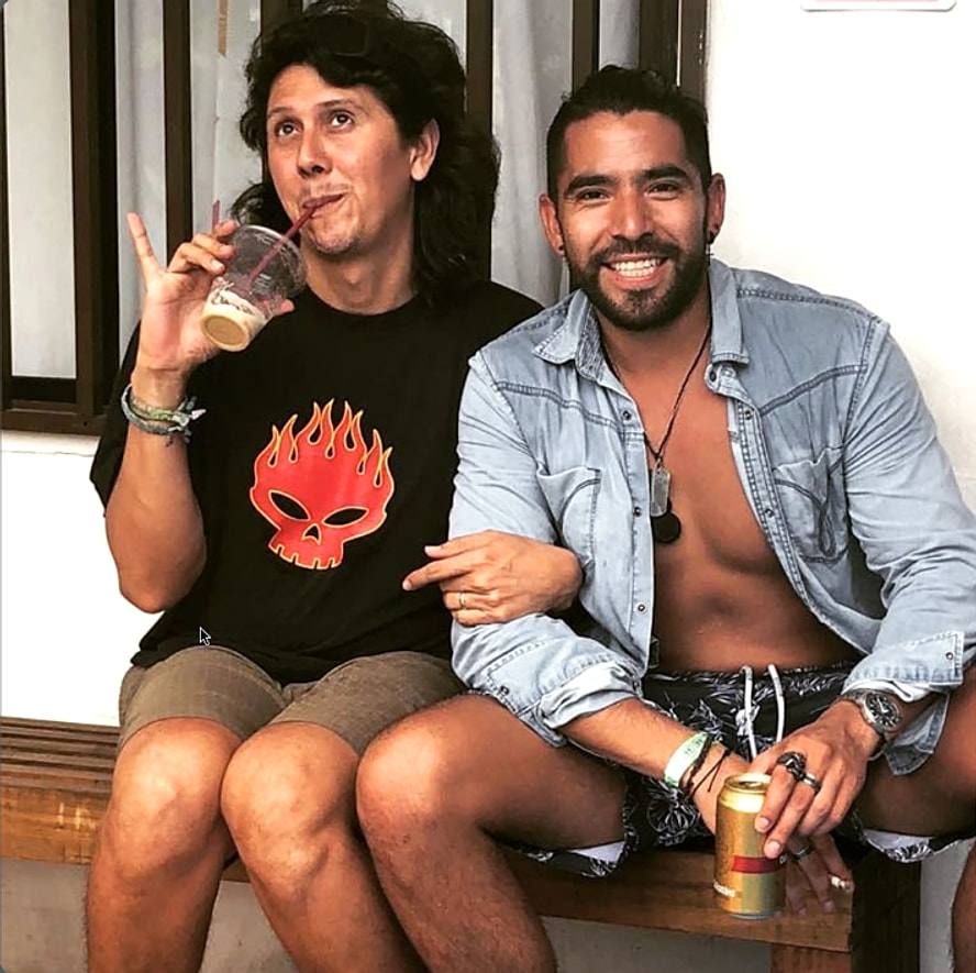 Juan, Blue Almond’s owner (left, curly hair, black T-shirt), sitting on a wooden bench with a guest.