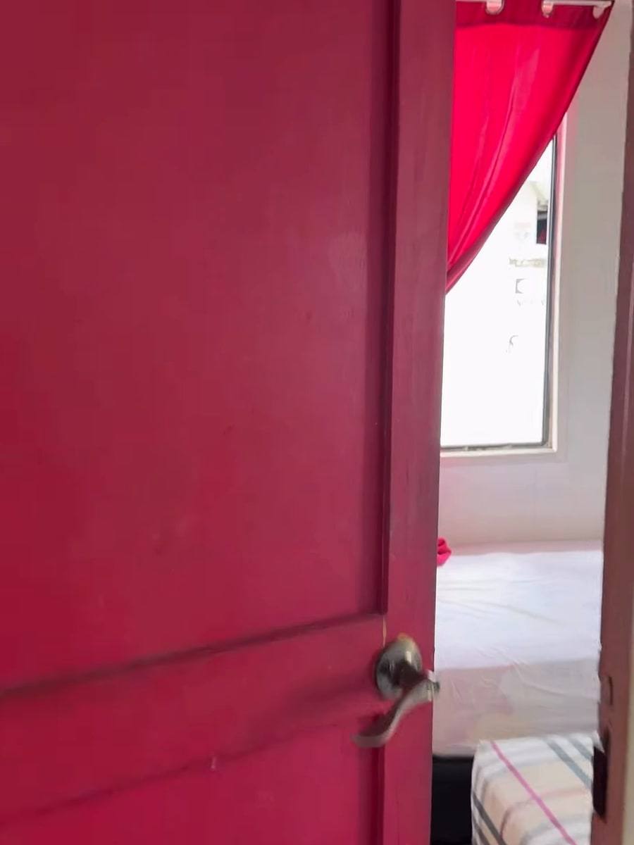 A bright pink door opening onto a room with a pink curtain.